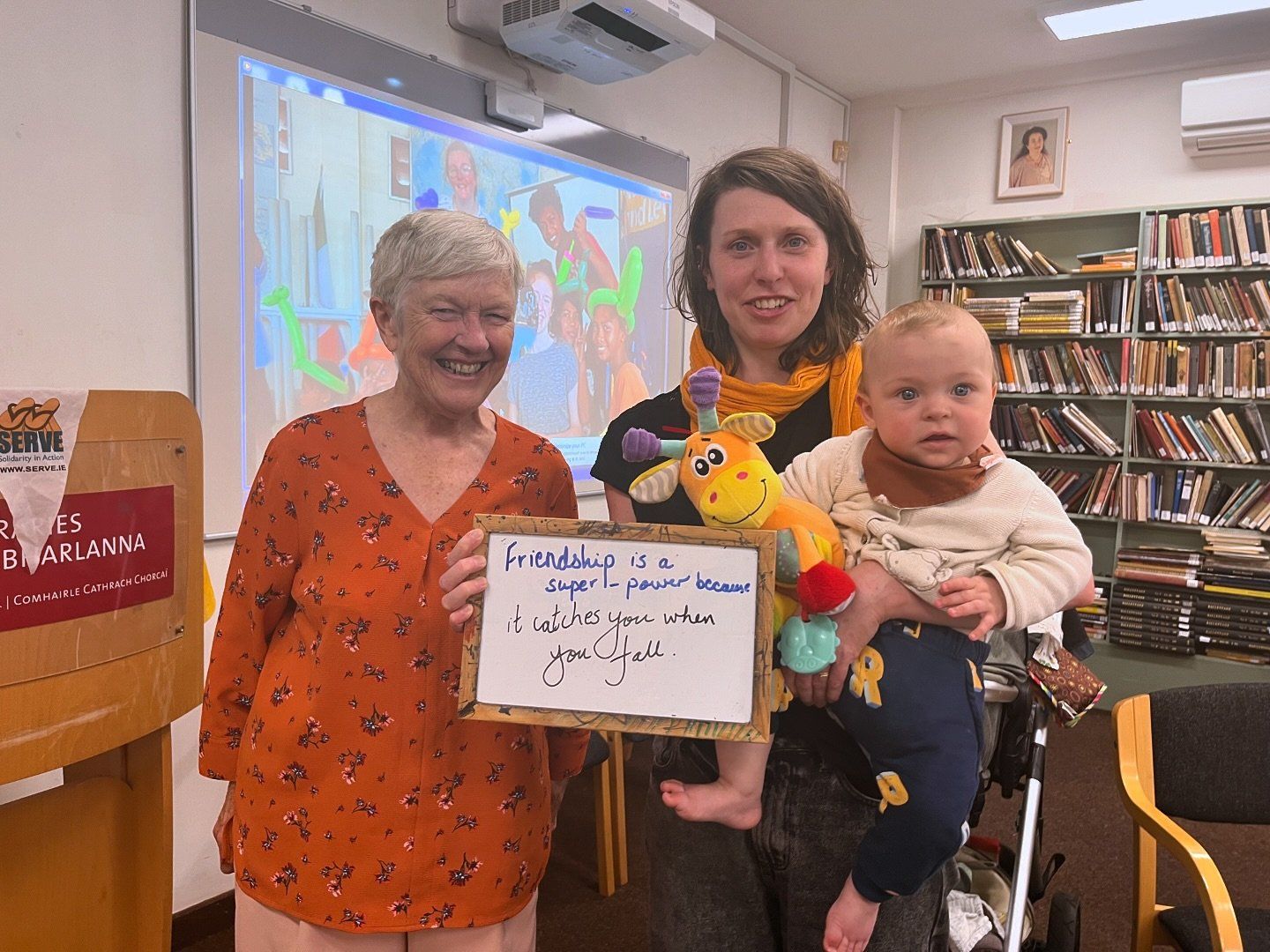 Friendship Cafe - two people standing, smiling with a baby