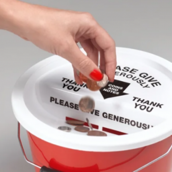 A hand wearing red nailpolish placing coins into a donation bucket.