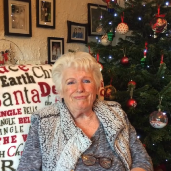 Noelle Fitzsimons, Community Hero of 2020, sits beside a Christmas tree
