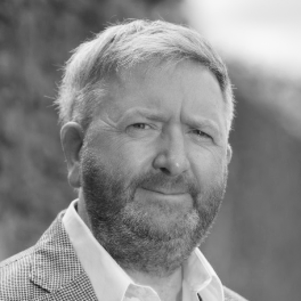 A black and white headshot of Barry Symes