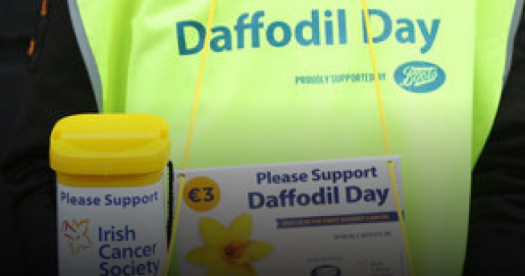 A volunteer in a hi-vis vest collects money for Daffodil Day.