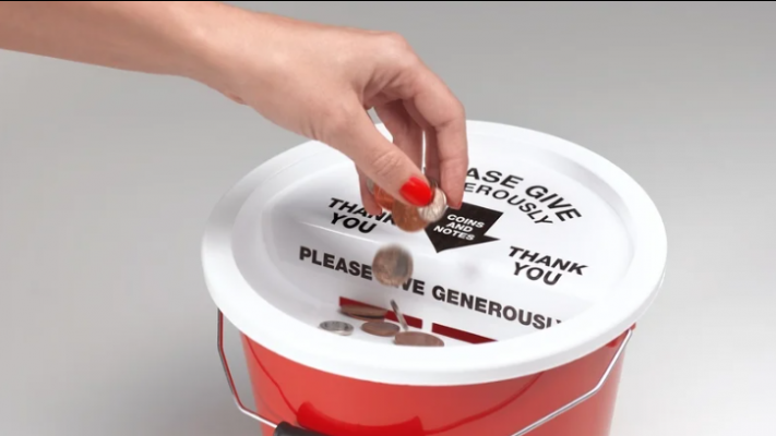 A hand wearing red nailpolish putting coins into a donation bucket.