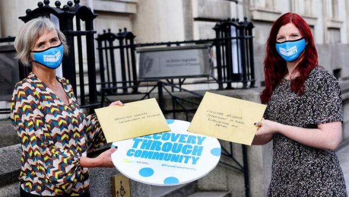 Two members of The Wheel staff holding The Wheel's 2021 budget submission.