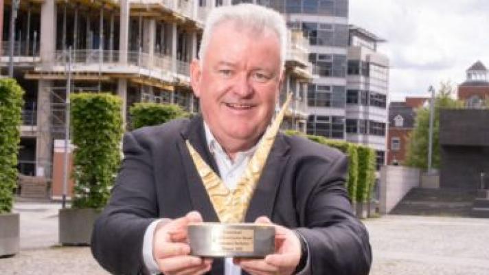 Diarmaid Ó Corrbuí, CEO of Carmichael, holding a trophy out towards the viewer.