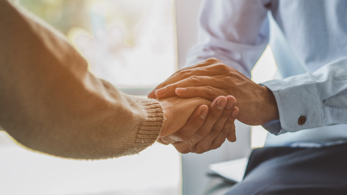 A close up image of one indiviudal holding anothers right hand between both of their hands. 