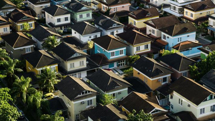 An image of a densely packed suburban area taken from above featuring dozens of brightly coloured houses intersperses with occasional tress. 