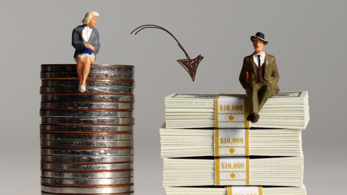 AN image of a figurine of a woman on a pile of coins slightly higher than a figurine of a man sitting on a pile of densely packed banknotes. 
