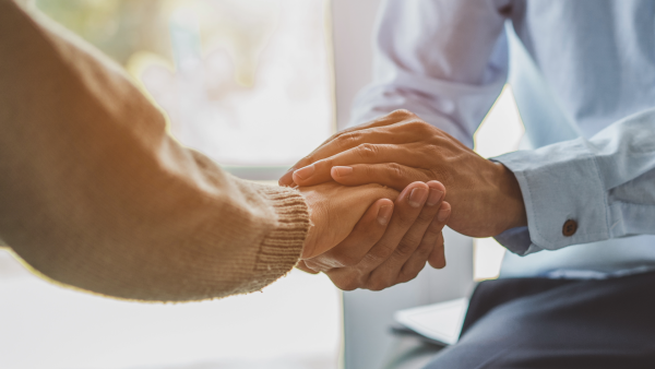 A close up image of one indiviudal holding anothers right hand between both of their hands.
