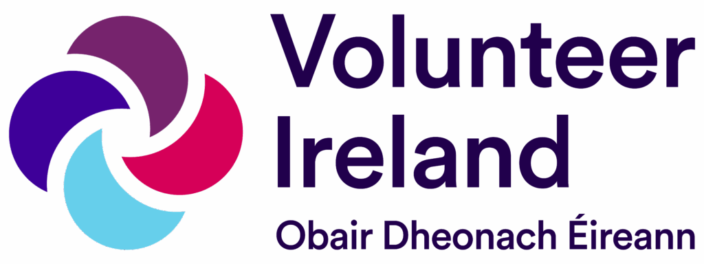 Logo for Volunteer Ireland showing a purple, red, and light blue abstract swirl, with the text Volunteer Ireland and the Irish translation Obair Dheonach Éireann in dark purple on a light background.