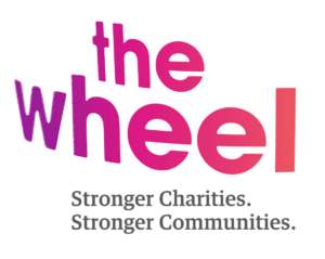 The logo for The Wheel, with the text Stronger Charities. Stronger Communities. underneath.
